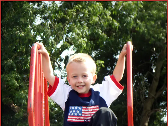 In this image, we can see a kid on the playground slide. There is a fencing at the bottom of the...