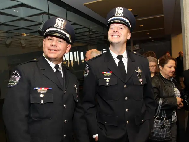 In the foreground of the picture there are two officers with smiley faces. In the center of the...